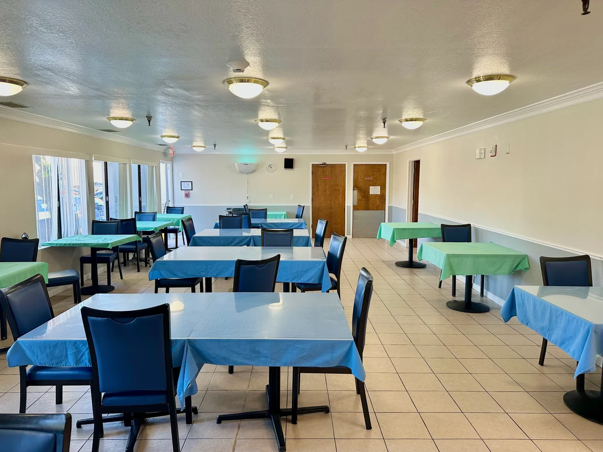 Light-filled dining room with tables and chairs at Millbrae Assisted Living Home