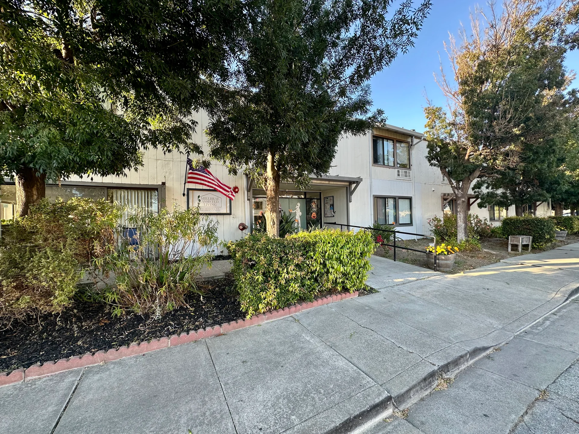 Tree-lined exterior and front entrance of Millbrae Assisted Living Home